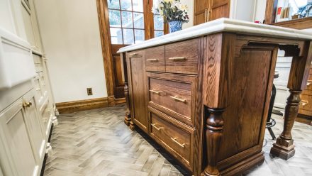 Fitted kitchen with wooden central island and light-colored worktop.