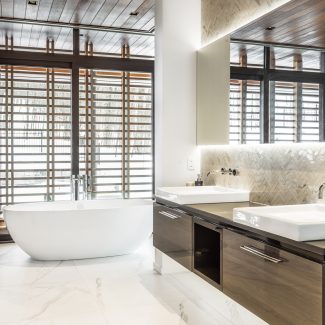 White bathroom with dark wood, refined bathtub and countertops in a residence in Tremblant.