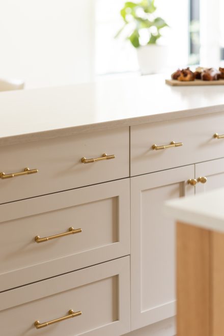 Détail de tiroirs crème avec poignées dorées, illustrant le raffinement des matériaux sur mesure.