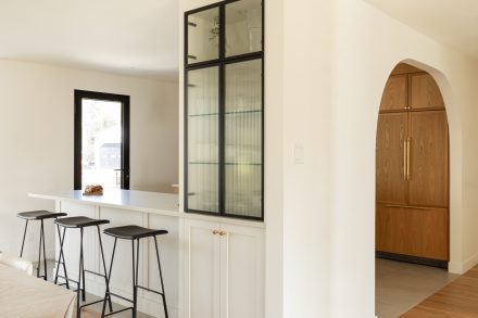 Vue d’ensemble d’une cuisine haut de gamme avec arches et rangements avec des portes cannelée, projet signé Ateliers Jacob.