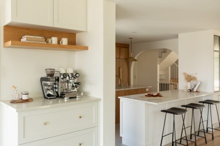 Vue d’ensemble d’une cuisine haut de gamme avec arches, coin barista et rangements en bois naturel.