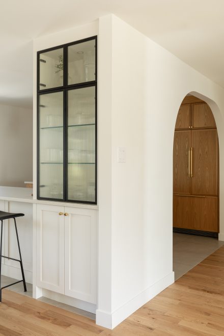 Vue d’ensemble d’une cuisine haut de gamme avec arches et rangements avec des portes cannelée, projet signé Ateliers Jacob.