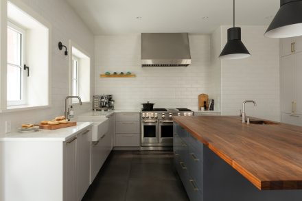 Cuisine lumineuse au style classique contemporain avec grand îlot en noyer, armoires shaker grises et blanches, et électroménagers haut de gamme en acier inoxydable.