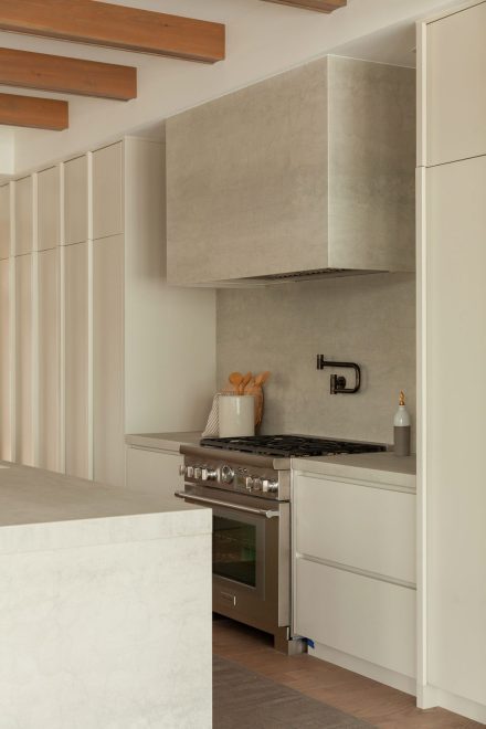 Cuisine Japandi réalisée par Ateliers Jacob, avec comptoir, hotte et dosseret en porcelaine formant une continuité élégante et apaisante.