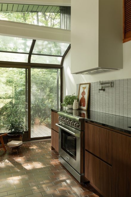 Cuisine Ateliers Jacob pour Cœur de Pirate, inspirée du style Mid-Century Modern, avec armoires en noyer, dosseret en céramique, comptoir sombre et ouverture sur l’extérieur.