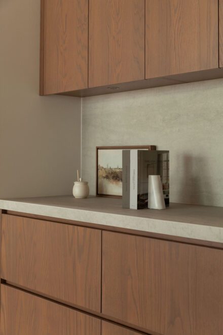 Cuisine Ateliers Jacob en chêne et laque, avec comptoirs et dosseret en porcelaine Laminam Pietra Di Savoia Perla. Une palette de matériaux où les textures naturelles et les surfaces minérales se complètent. Conception et Cuisiniste : Ateliers Jacob | Design : Symbiose Design
