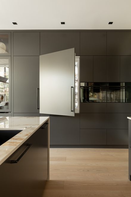 Ateliers Jacob a dissimulé un réfrigérateur derrière des panneaux assortis aux armoires, créant ainsi une intégration fluide et minimaliste. Photo : Ateliers Jacob