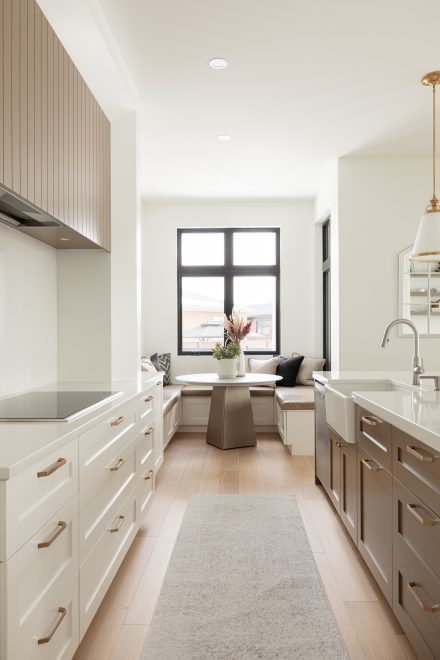 Une cuisine lumineuse et moderne avec des armoires blanches sur mesure, un îlot central en tons neutres et des accents dorés.