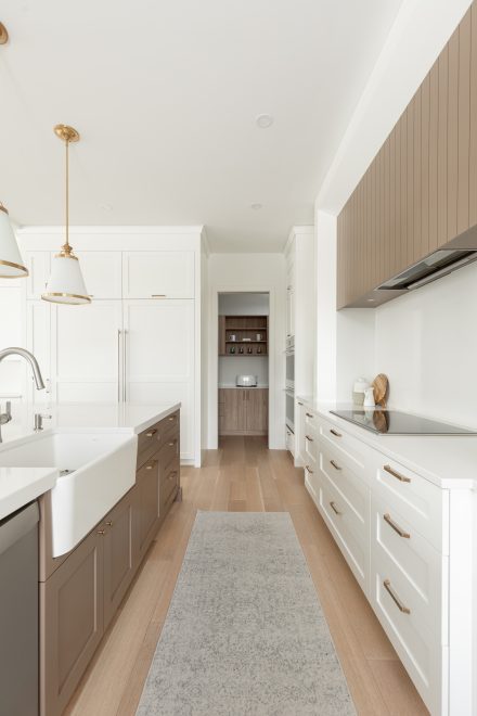 Vue axiale d’une cuisine moderne blanche avec dosseret épuré, rangements symétriques et garde-manger en retrait.