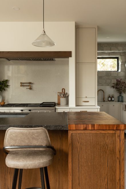 Cuisine haut de gamme avec comptoir en pierre noire, planche de boucher intégrée et robinet mural au-dessus de la cuisinière.