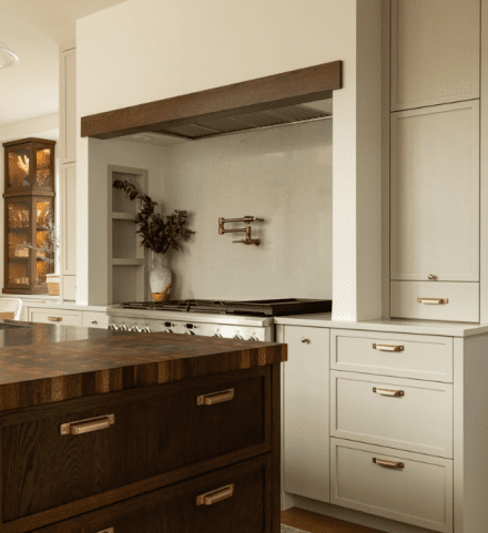 Cuisine avec îlot central en bois de type butcher block, combiné à des armoires shaker crème.