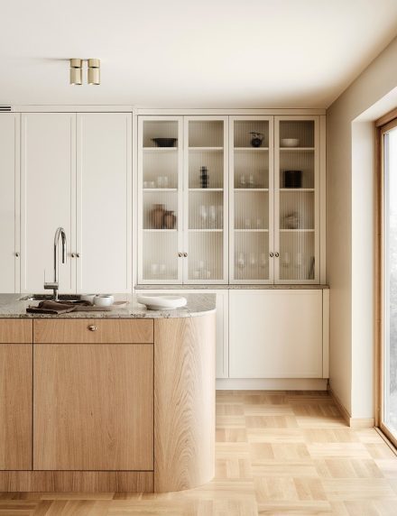 Classic beige country kitchen from Nordiska Kök with kitchen island in light wood and rounded corners. Beautiful built-in display cabinet with glass doors and countertop in Lemon Ice granite.