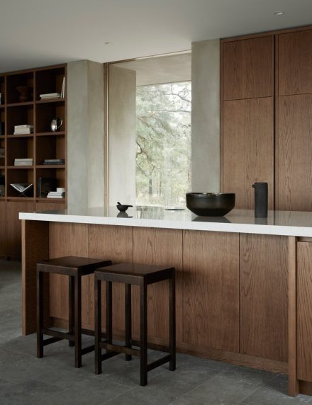 Architect-designed house in concrete with a bespoke wooden kitchen in dark oak from Nordiska Kok. Scandinavian minimalist interior design with concrete walls and floors. A modern home with smart hidden storage solutions and a beautiful site-built wooden bookshelf.