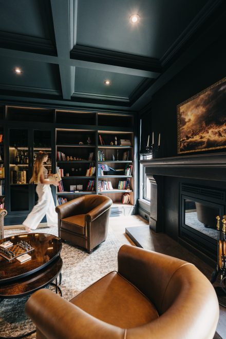 Salon élégant conçu par Ateliers Jacob avec bibliothèque sur mesure, fauteuils en cuir, foyer noir et ambiance feutrée propice à la lecture et à la détente.