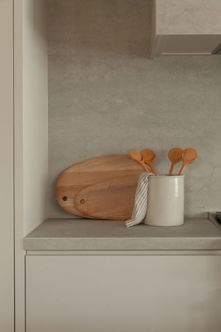 Planche en bois et ustensiles artisanaux posés sur un comptoir en porcelaine Laminam, dans une cuisine signée Ateliers Jacob.