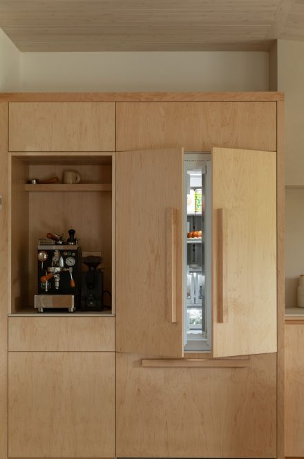 Cuisine Ateliers Jacob avec réfrigérateur encastré et armoires en érable clair, conçues pour être durables et faciles à entretenir.