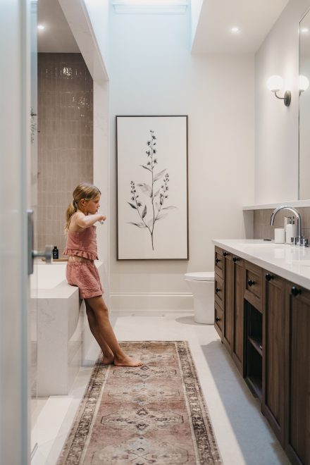 Salle de bain familiale conçue par Ateliers Jacob, avec vanité en bois, puits de lumière et aménagement pensé pour le bien-être et l’usage quotidien.