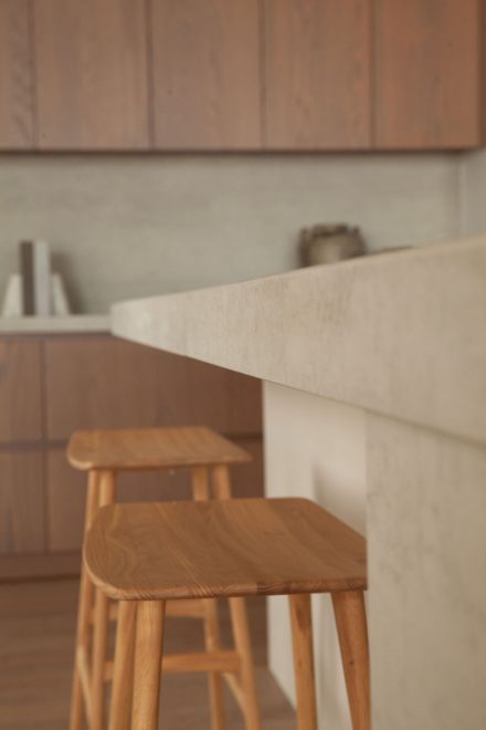 Planche en bois et ustensiles artisanaux posés sur un comptoir en porcelaine Laminam, dans une cuisine signée Ateliers Jacob.