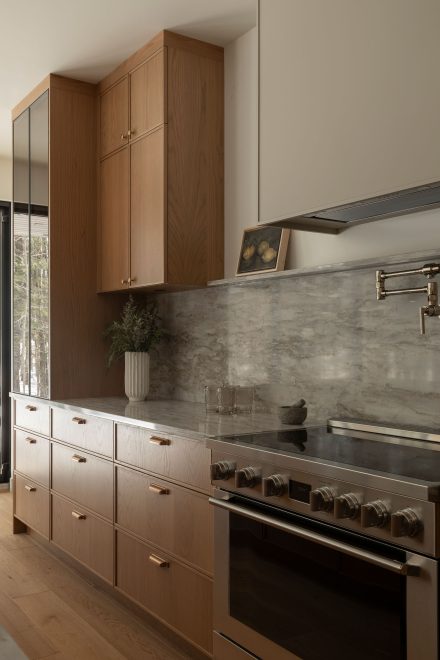 Cuisine contemporaine sur mesure conçue par Ateliers Jacob, combinant armoires en chêne naturel, quartz gris et hotte intégrée discrète. 