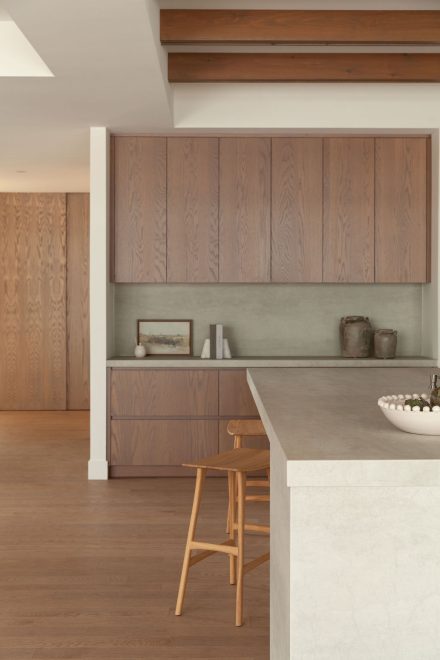 Armoires en chêne vertical et comptoir en surface minérale dans la cuisine Farand de Ateliers Jacob.