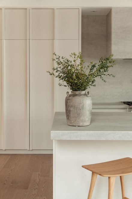 Vase en terre cuite sur le comptoir en surface minérale de la cuisine Farand, soulignant l’équilibre des matières naturelles.