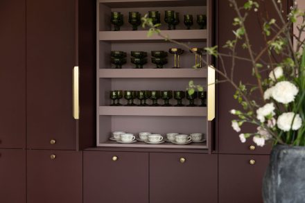 Armoire sur mesure Ateliers Jacob avec vaisselle exposée dans des armoires bourgogne et finition haut de gamme