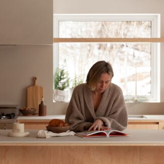 une femme dans sa cuisine Ateliers Jacob en train de regarder un livre de recette en papier