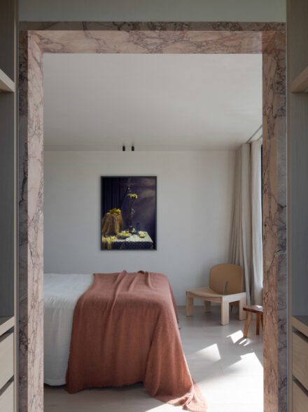 Chambre encadrée d’une ouverture en pierre menant à un walk-in sur mesure discret, garde-robe intégré dans une composition épurée