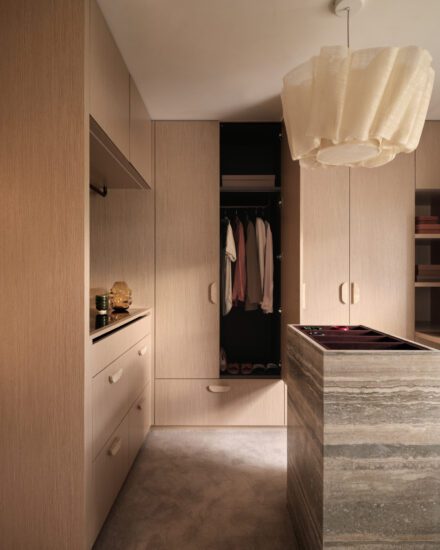 Walk-in sur mesure avec garde-robe intégré en bois clair, îlot central en pierre et rangement structuré pour une organisation fluide