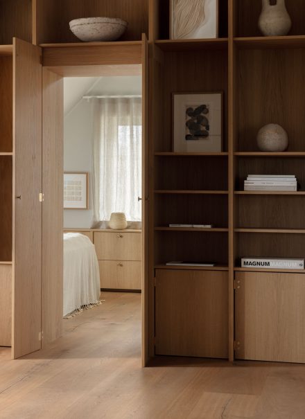 Au deuxième étage de cette habitation se trouve une bibliothèque en chêne blanc qui s’intègre parfaitement au décor, dissimulant une porte menant de la chambre principale au salon. Projet : Strandgården de Norm Architects | Photo: Jonas Bjerre-Poulsen, Karl Tranberg Knudsen, Sandie Lykke Nolsøe
