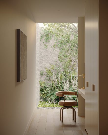 Un coin bureau discrètement intégré crée une transition apaisée entre les sphères de vie, encadré par la verdure et baigné d’une lumière douce et diffuse.