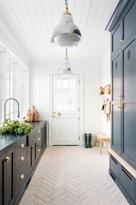 Mudroom blanc avec armoires gris-bleu, comptoir en pierre naturelle soapstone et plancher en carreaux de ciment motif chevron.
