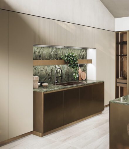 Cuisine aux lignes adoucies, façades métalliques brunies et comptoir en marbre Verde Borgogna aux veines profondes, lumière naturelle filtrée révélant la matière. Projet GF Interiors par Guzzini & Fontana.
