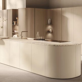 Cuisine Scavolini présentée à l’EuroCucina 2026, îlot aux lignes arrondies en finition crème et plan de travail en pierre claire, lumière naturelle et bois clair en arrière-plan