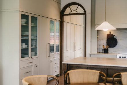 cuisine Ateliers Jacob haut de gamme avec armoires pleine hauteur, vitrines intégrées et îlot central fonctionnel en bois