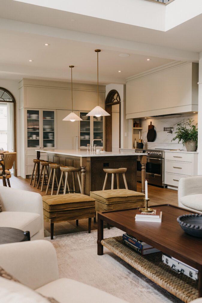 cuisine Ateliers Jacob en aire ouverte avec îlot central, tabourets en bois, salle à manger lumineuse et matériaux naturels