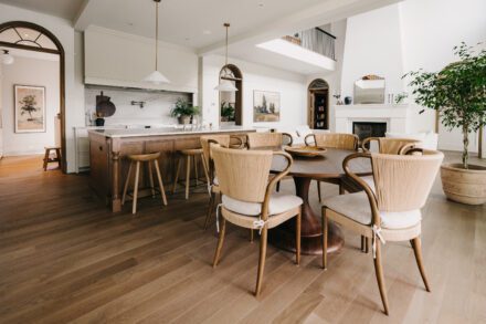 cuisine Ateliers Jacob en aire ouverte avec îlot central en bois, salle à manger intégrée, plafond double hauteur et aménagement fluide reliant cuisine et salon