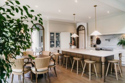 cuisine Ateliers Jacob avec îlot central en bois, luminaires suspendus et ouverture vers salle à manger