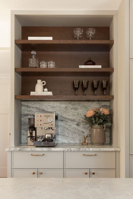 Coin café Ateliers Jacob avec étagères ouvertes en bois foncé, dosseret en quartzite et rangement intégré sur mesure dans une cuisine haut de gamme.