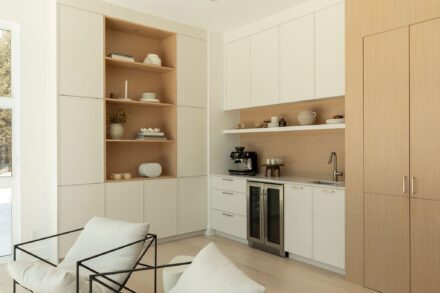 Coin café et rangement intégré dans une cuisine minimaliste Ateliers Jacob, avec bois naturel, armoires crème et électroménagers encastrés