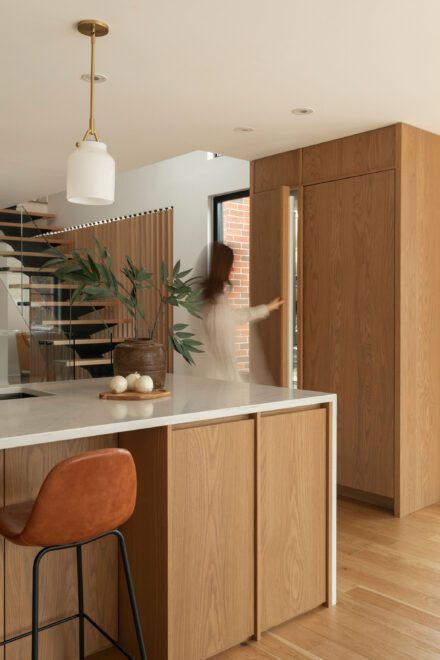 Cuisine Ateliers Jacob en chêne naturel et quartz blanc avec îlot central, rangement pleine hauteur dissimulé et aménagement minimaliste baigné de lumière naturelle.