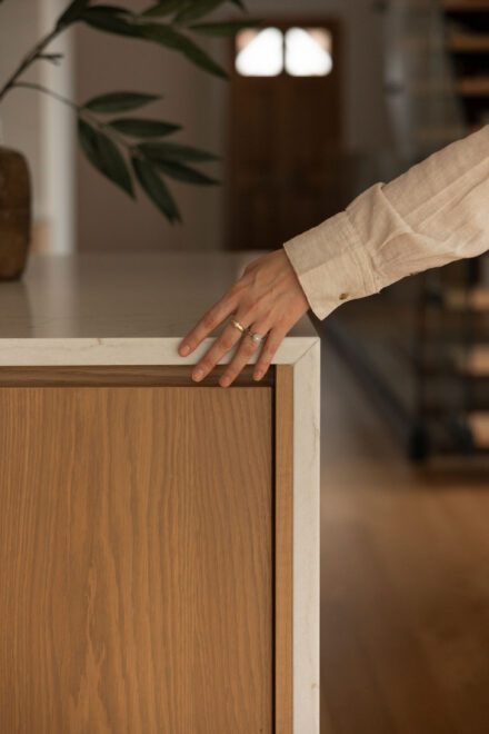 Détail d’une cuisine Ateliers Jacob en chêne et quartz avec finition sur mesure, angle de comptoir épuré et matériaux naturels dans un aménagement haut de gamme contemporain.