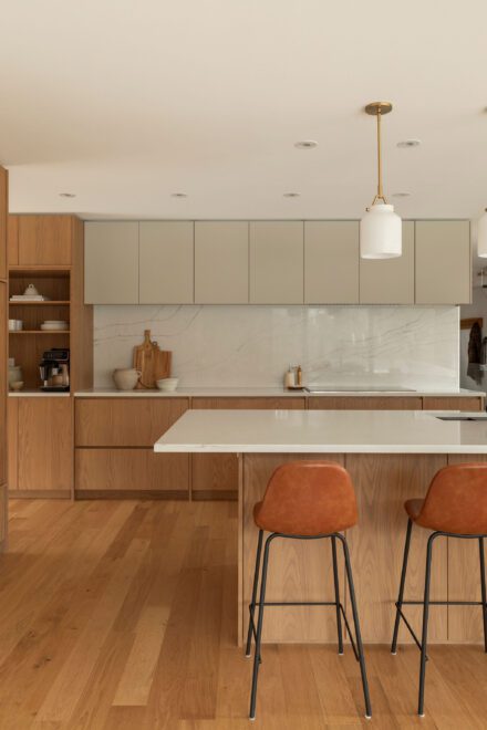 Cuisine Ateliers Jacob en chêne blanc et quartz clair avec îlot minimaliste, armoires intégrées pleine hauteur et dosseret en pierre veinée dans une demeure contemporaine à Montréal.