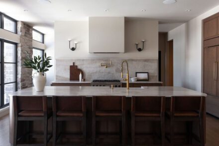 Cuisine Ateliers Jacob avec dosseret en quartzite naturel, armoires en bois brun foncé et robinetterie en laiton
