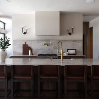 Cuisine Ateliers Jacob avec dosseret en quartzite naturel, armoires en bois foncé et robinetterie en laiton dans une cuisine haut de gamme intemporelle