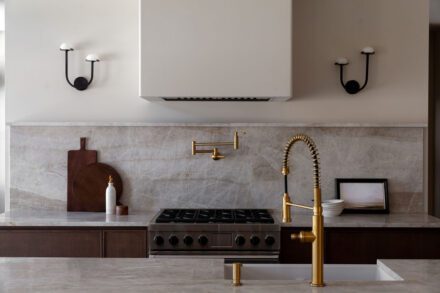 Cuisine Ateliers Jacob avec dosseret en quartzite naturel, armoires en bois brun foncé et robinetterie en laiton