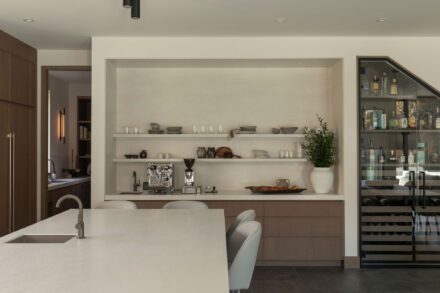 Coin café intégré dans une cuisine Ateliers Jacob avec étagères ouvertes, mobilier en chêne, comptoir de porcelaine et cellier vitré haut de gamme conçu avec Symbiose Design.