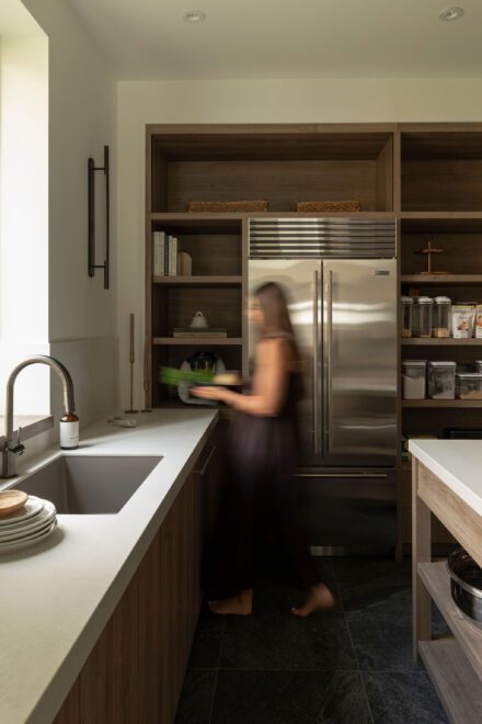 Arrière-cuisine Ateliers Jacob conçue avec Symbiose Design, avec comptoirs de porcelaine, mobilier en bois de chêne, rangement ouvert intégré et circulation fluide pensée pour le quotidien.
