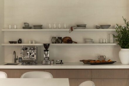 Détail d’un coin café sur mesure Ateliers Jacob avec étagères ouvertes, machine espresso, comptoir de porcelaine et mobilier en bois de chêne aux lignes minimalistes.