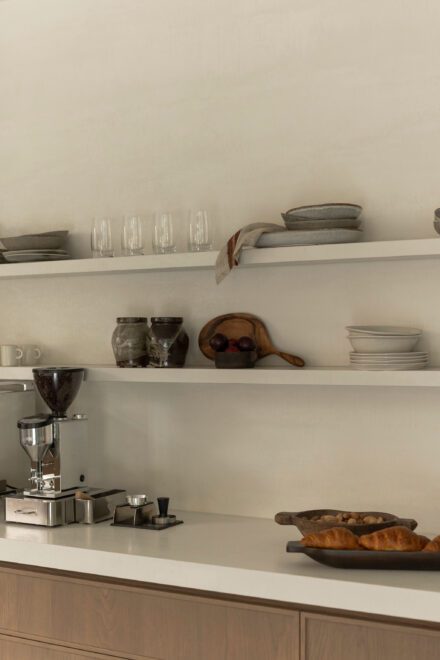Détail d’un coin café minimaliste Ateliers Jacob conçu avec Symbiose Design, avec étagères ouvertes, comptoir de porcelaine, mobilier en bois de chêne et accessoires aux matières naturelles dans une cuisine haut de gamme.